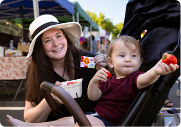 Mom holding WIC Card, child holding strawberry